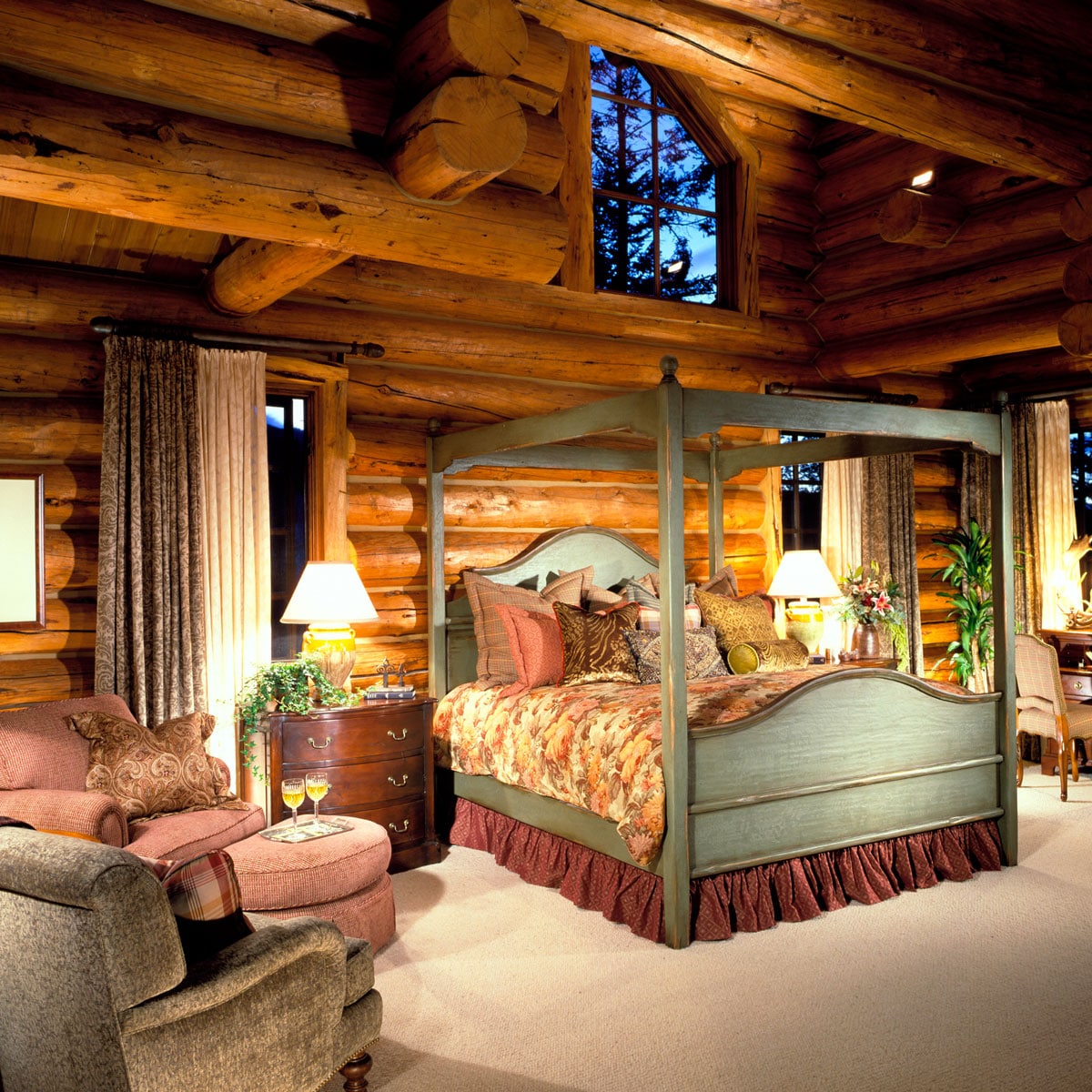 luxurious master suite in a log cabin with a large, plush bed with a dark brown headboard, adorned with a white duvet and throw pillows.