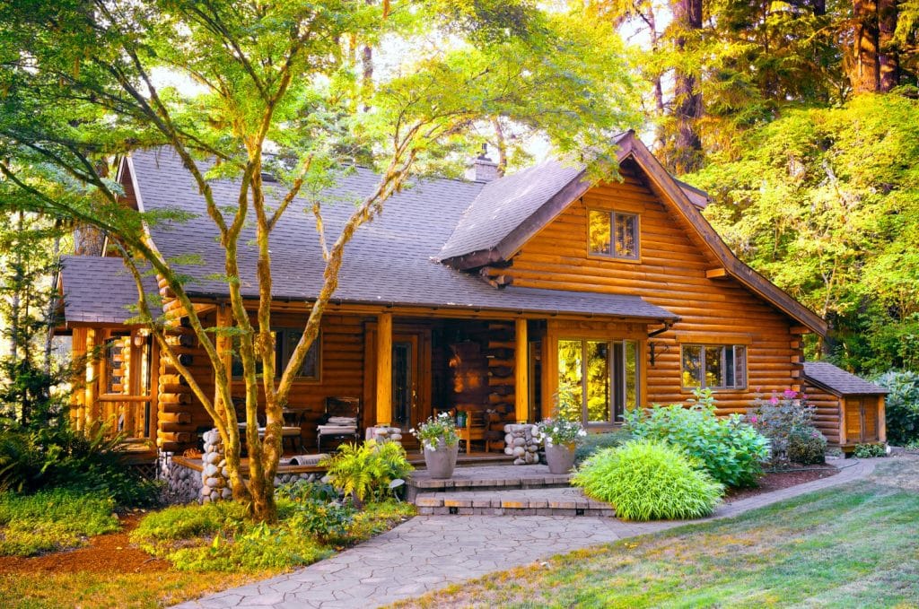 Family log home surrounded by beautiful nature showing the benefits of living in a log home in harmony with nature | Frontier Log Homes