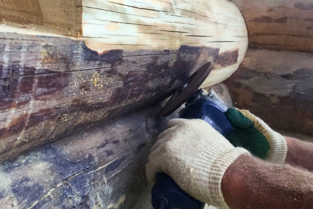 Man Staining Log Home Exterior For Treatment