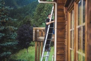 Autumn log home maintenance clearing gutters before winter