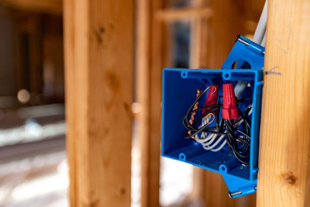 Log cabin wiring in progress with cable routed through a bored log wall