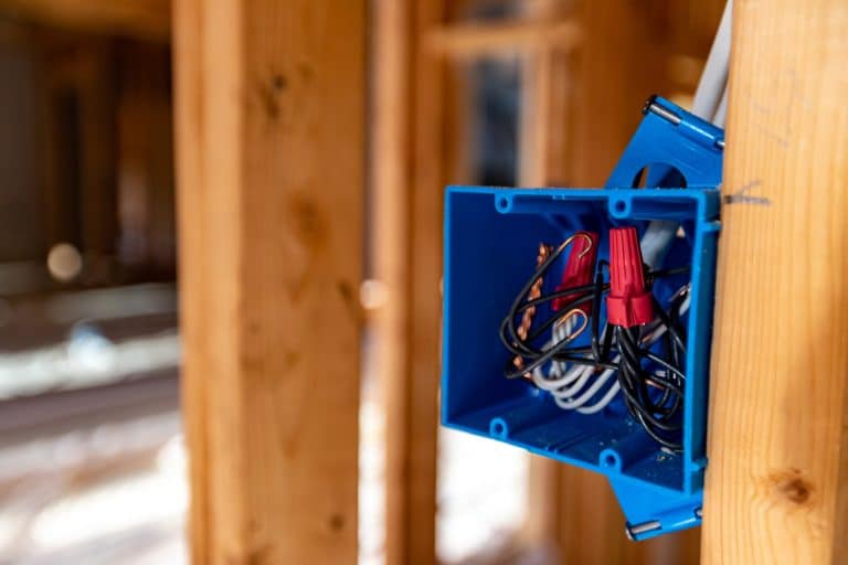 Log cabin wiring in progress with cable routed through a bored log wall